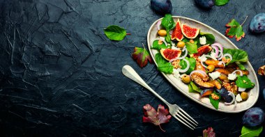 Autumn salad with plums,figs,olives and cheese.Seasonal salad of fruits and nuts.Space for text