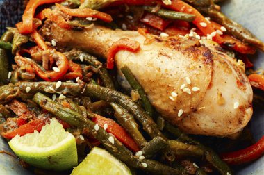 Delicious chicken legs grilled with asparagus beans and carrots. Close up