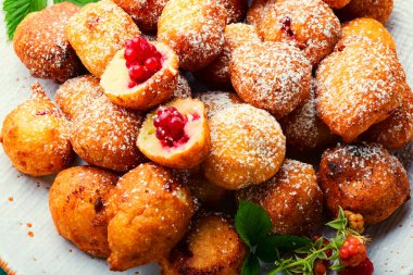 Kızarmış süzme peynirli çörek ve böğürtlenli çörek. Tabakta donut.