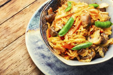 Vejetaryen yemeği, havuçlu haşlanmış lahana ve ahşap masa üzerinde mantar.