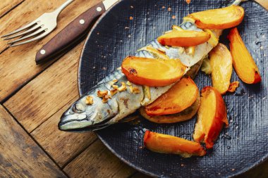 Deniz ürünleri, kızarmış uskumru. Kırsal ahşap masada hurma meyvesi ile balık scomber