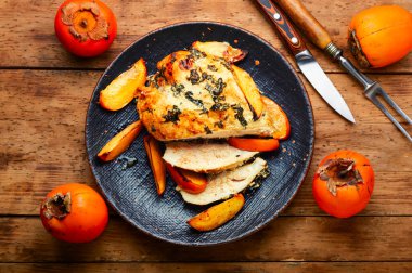 Hurmayla kızartılmış lezzetli tavuk eti. Eski ahşap masada meyveli tavuk göğsü.