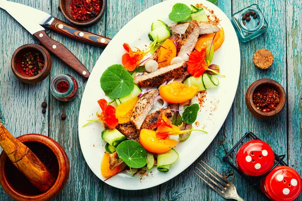 Meat steak decorated with nasturtium flowers. Sliced pork steak, salad.