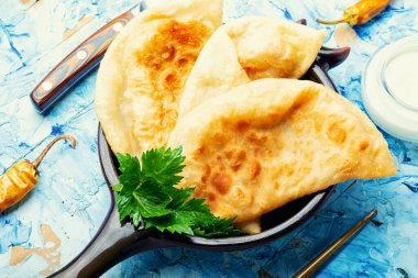 Cheburekler, et dolu kızarmış hilal şeklinde kekler. Ev yapımı kızarmış cheburek turtaları.