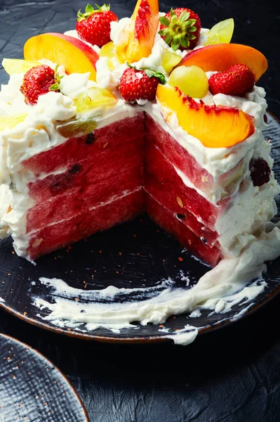 Bright summer watermelon cake. Watermelon cake with whipped cream, decorated with berries and fruits.