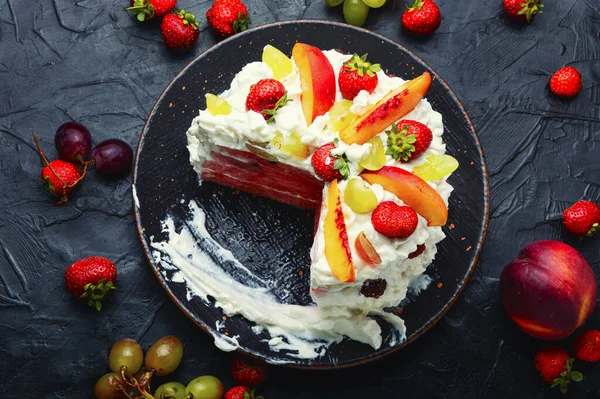 Colorful summer watermelon cake. Watermelon cake with whipped cream, decorated with berries and fruits.