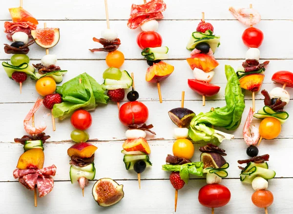 Karides, jamon, ahşap şiş üzerinde meyve ve sebze ziyafeti..