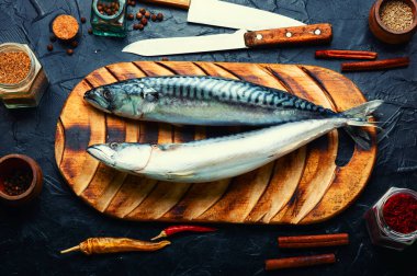 Mutfak masasında çiğ uskumru balığı ve baharat var. Deniz ürünleri.