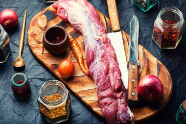 Kesme tahtasında pişirmek için çiğ domuz eti. Çiğ et filetosu ve baharat.