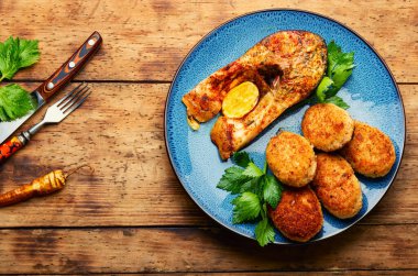 Baked fish cutlets and tasty fish steak on rural wooden surface