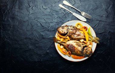 Delicious fried fish dorada with fruits and spices. Copy space