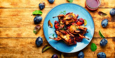 Erik soslu kızarmış bıldırcın. Ahşap masada erikli et