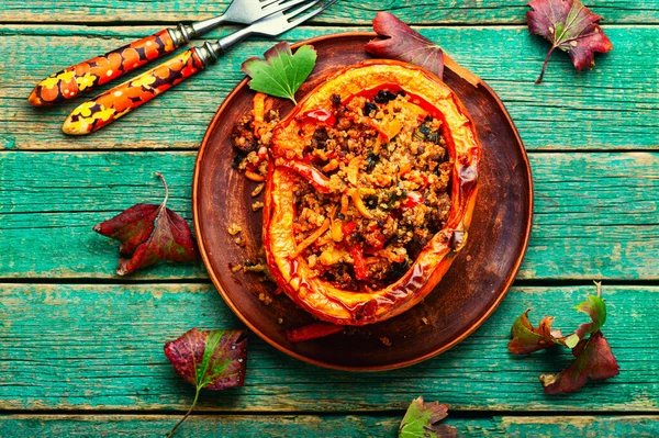 Baked pumpkin stuffed with vegetables, a popular autumn food.Roasted squash, wooden table