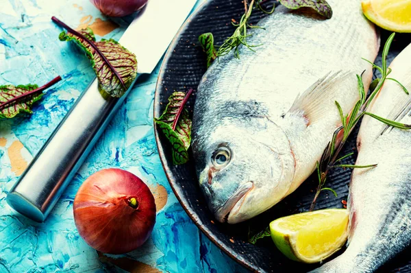 Two raw dorado fish for cooking on a plate.