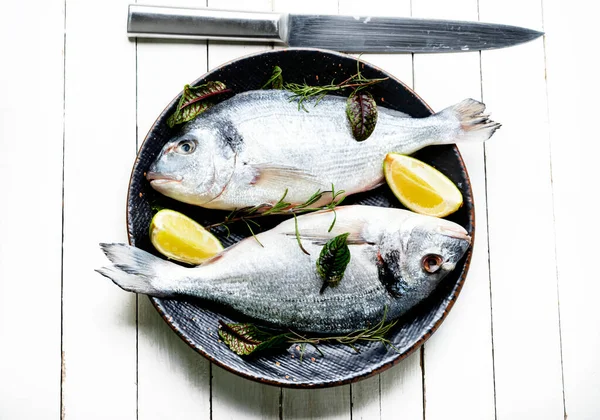 Two raw dorado fish for cooking on a plate. Seafood on white background