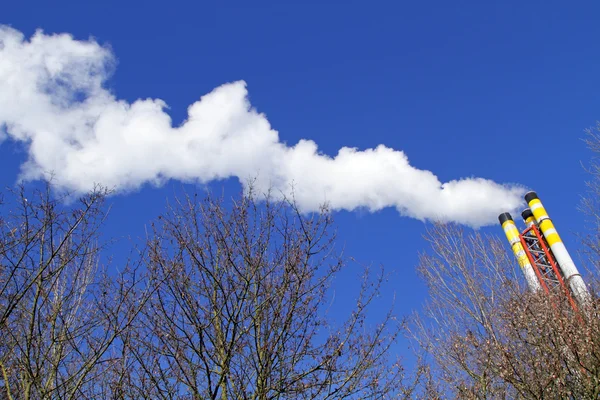 Chaminé emitindo fumaça contra um céu azul — Fotografia de Stock