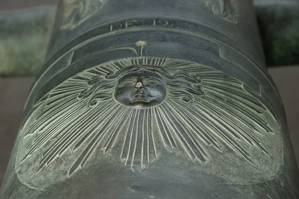 A fragment of the coat of arms of King of France Louis XIV (Sun King) on the old bronze cannon. — Stock Photo, Image