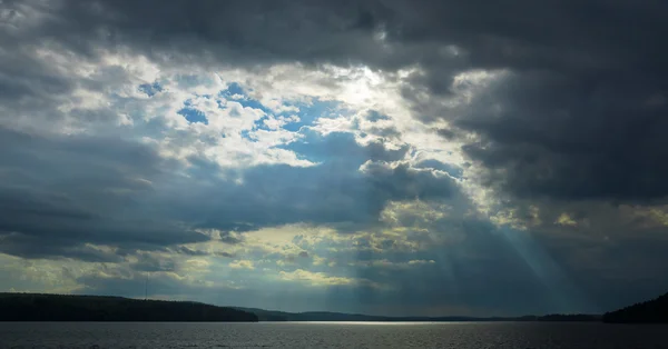 Cloudy sky over the lake. Rays of light through the clouds. — Stock Photo, Image