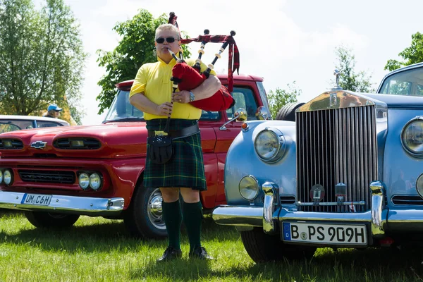 PAAREN IM GLIEN, GERMANY - MAY 19: Piper plays the Great Highland Bagpipe near the car Rolls-Royce Silver Cloud, The oldtimer show in MAFZ, May 19, 2013 in Paaren im Glien, Germany — Stock Photo, Image