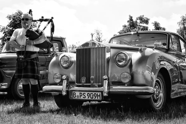 PAAREN IM GLIEN, GERMANY - MAY 19: Piper plays the Great Highland Bagpipe near the car Rolls-Royce Silver Cloud, black and white, The oldtimer show in MAFZ, May 19, 2013 in Paaren im Glien, Germany — Stock Photo, Image