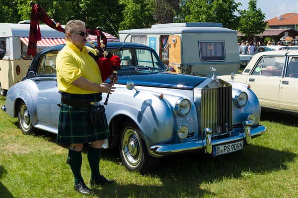 PAAREN IM GLIEN, GERMANY - MAY 19: Piper plays the Great Highland Bagpipe near the car Rolls-Royce Silver Cloud, The oldtimer show in MAFZ, May 19, 2013 in Paaren im Glien, Germany — Stock Photo, Image