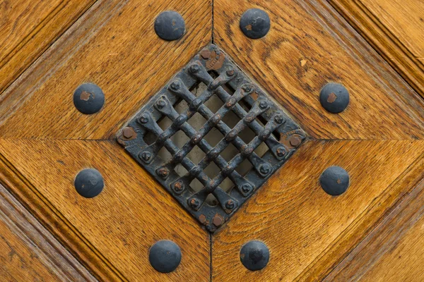 Fragment of old wooden door with grille and rivets — Stock Photo, Image
