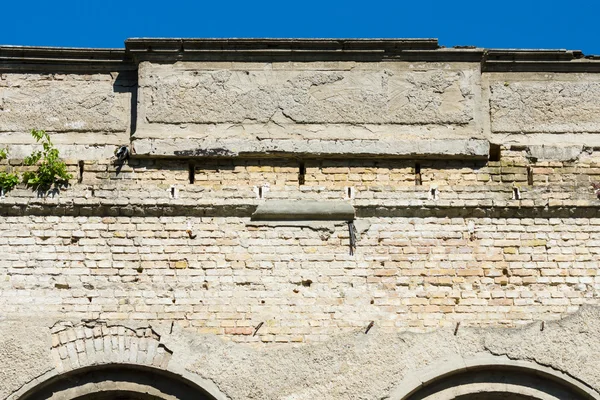 Old brick wall of the building and crumbling plaster. Fragment of a blue sky. — Stock Photo, Image