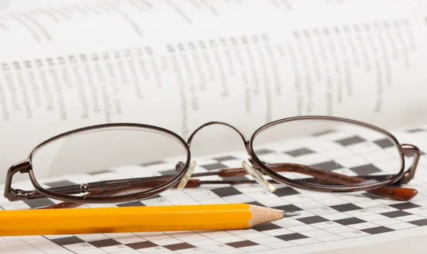 Lápiz y gafas en un crucigrama — Foto de Stock