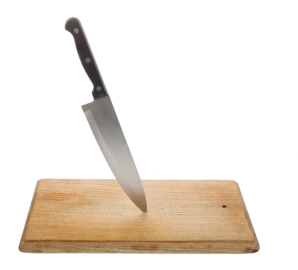 Knife on an old worn and scratched wooden cutting board — Stock Photo, Image
