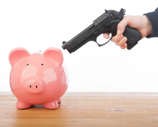 Homem apontando uma arma para um banco porquinho — Fotografia de Stock