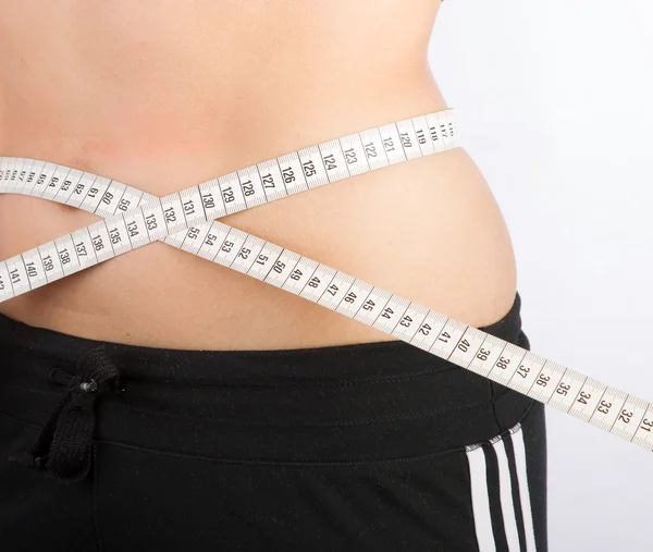 Woman measuring her waist with tape measure — Stock Photo, Image