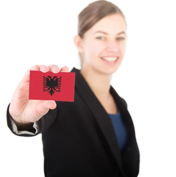 Mujer de negocios sosteniendo una tarjeta con la bandera de Albania —  Fotos de Stock