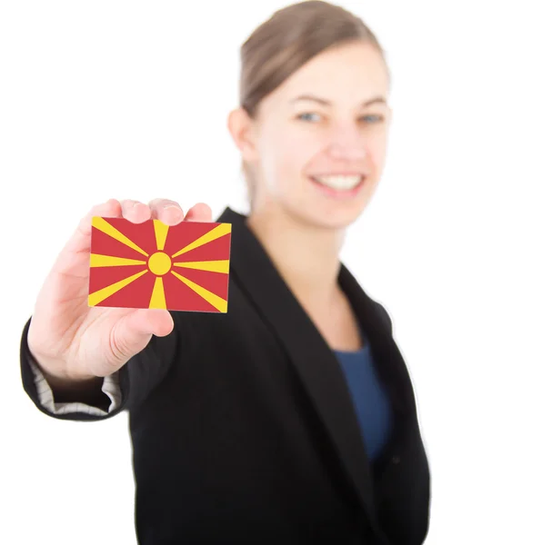 Mulher de negócios segurando um cartão com a bandeira da Macedônia — Fotografia de Stock