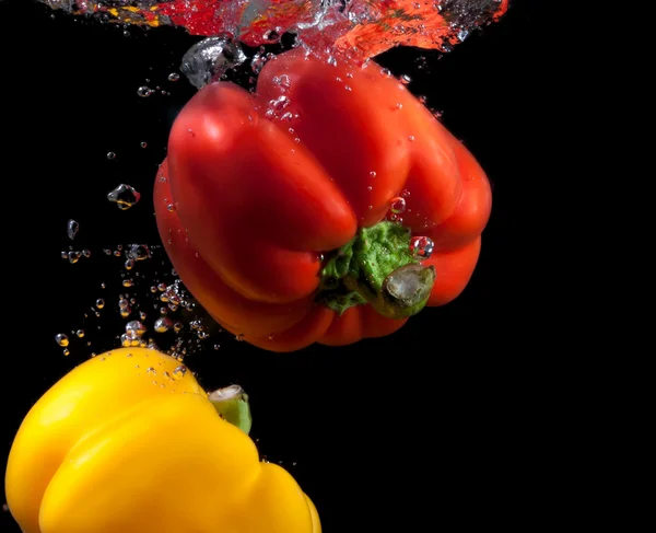Gele en rode paprika plons in water. — Stockfoto