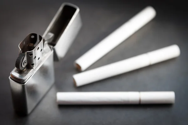 Open metal lighter and three cigarettes. — Stock Photo, Image