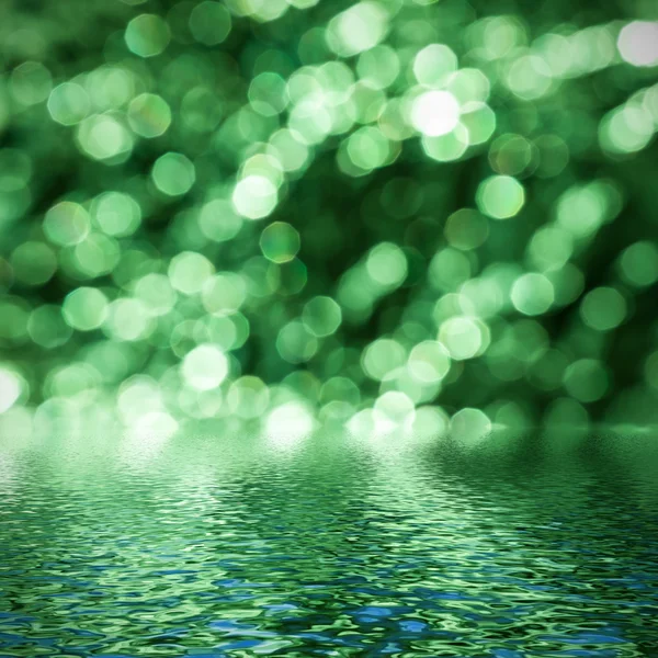 Groene bokeh weerspiegeld in water. — Stockfoto