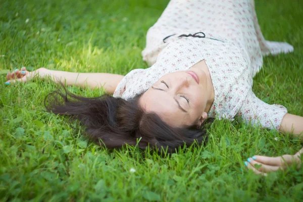 Brunette lying in the grass. — Stock Photo, Image