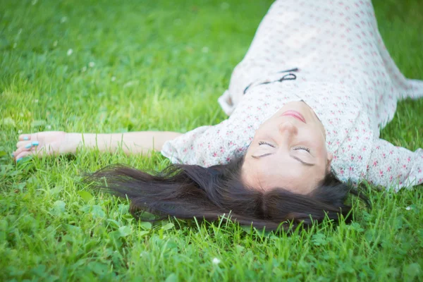 Brunette lying in the grass. — Stock Photo, Image