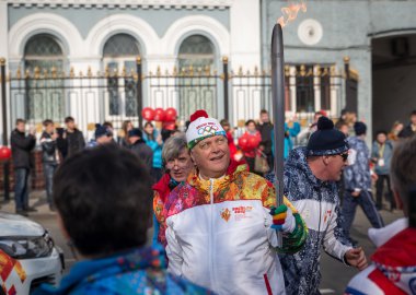 Olimpiyat meşalesinin ışık tutan kimse taşır.