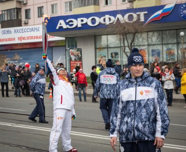 Olimpiyat meşalesinin ışık tutan kimse taşır.