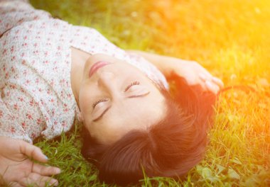 Genç kadın çimlerin üzerinde yatıyor..