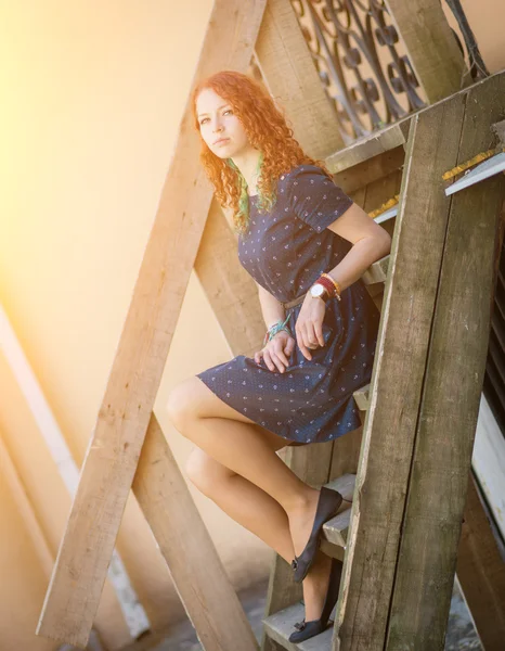 Redhead girl sitting on old wooden stairs. — Stock Photo, Image