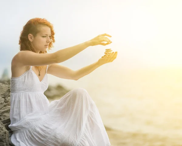 Woman holding zen stones in hand with sea background. — Stock Photo, Image