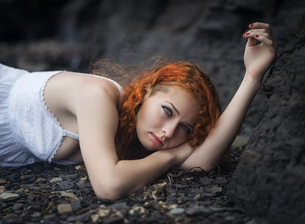 Redhead vrouw gelegd naar beneden op de gravel. — Stockfoto