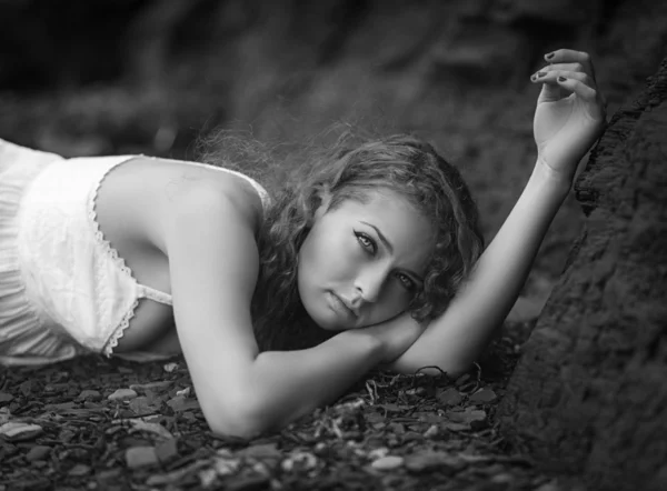 Beautiful woman laid down on the gravel. — Stock Photo, Image