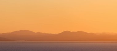 Günbatımı gökyüzünün arka planında deniz manzarası.