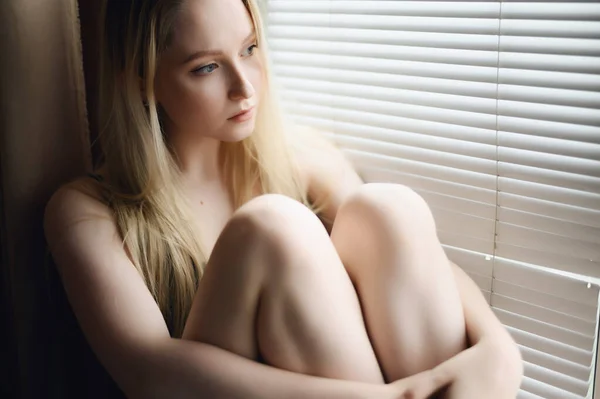 多愁善感的年轻女子坐在窗台上 — 图库照片