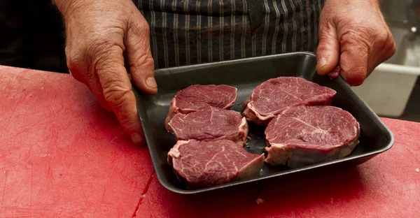 Carnicero cuidadosamente embalaje de carne en una bandeja — Foto de Stock