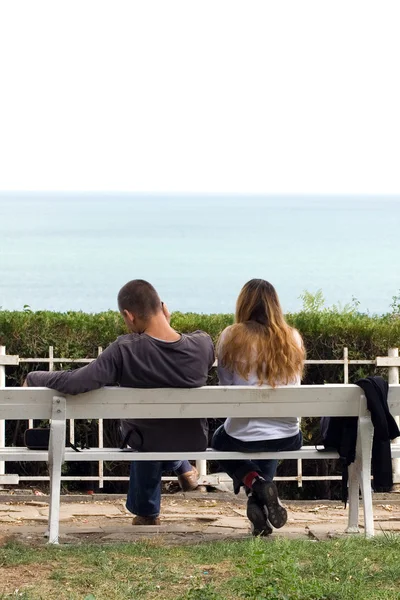 Young couple sitting in a bench — Stock Photo, Image