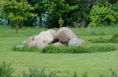 Pile of big stones in green grass on the meadow